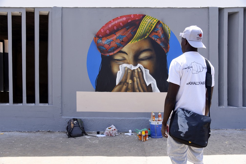 21 de março - Artistas do grupo senegalês de grafite RBS Crew finalizam o desenho de uma mulher cobrindo o nariz com um lenço enquanto espirra, medida recomendada para prevenção contra o coronavírus, em um centro universitário de Dakar, no Senegal — Foto: Seyllou/Reuters