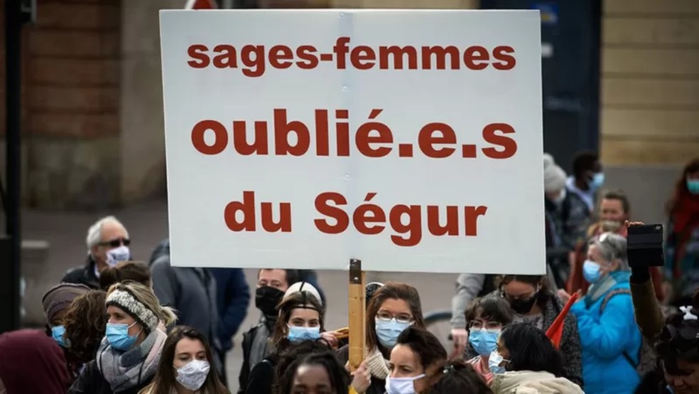 Na França, pessoas usam pontos para a linguagem inclusiva, como é possível ver no cartaz do protesto — Foto: Getty Images/Via BBC