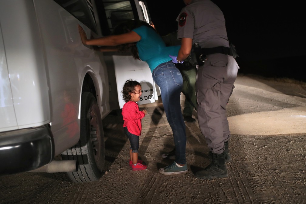 Criança de dois anos chora ao sua mãe ser revistada e detida em McAllen, nos EUA, perto da fronteira com o México, em foto de 12 de junho (Foto: JOHN MOORE / GETTY IMAGES NORTH AMERICA / AFP)