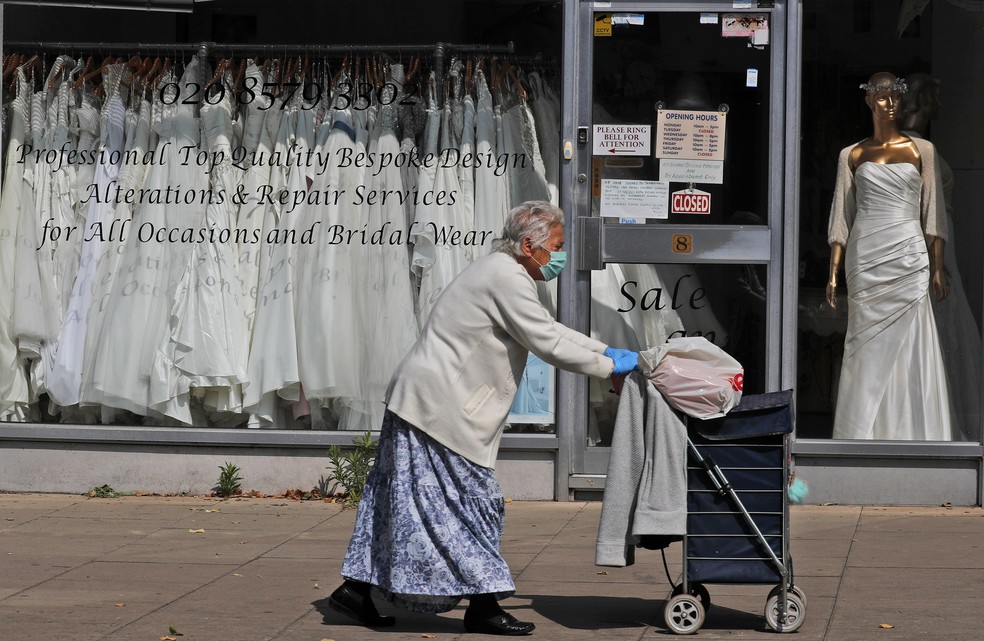 9 de junho - Mulher passa por loja de roupas de casamento onde vestidos de noiva se amontoam na vitrine, em Londres. Os casamentos no Reino Unido foram adiados devido à pandemia do coronavírus (Covid-19) — Foto: Frank Augstein/AP