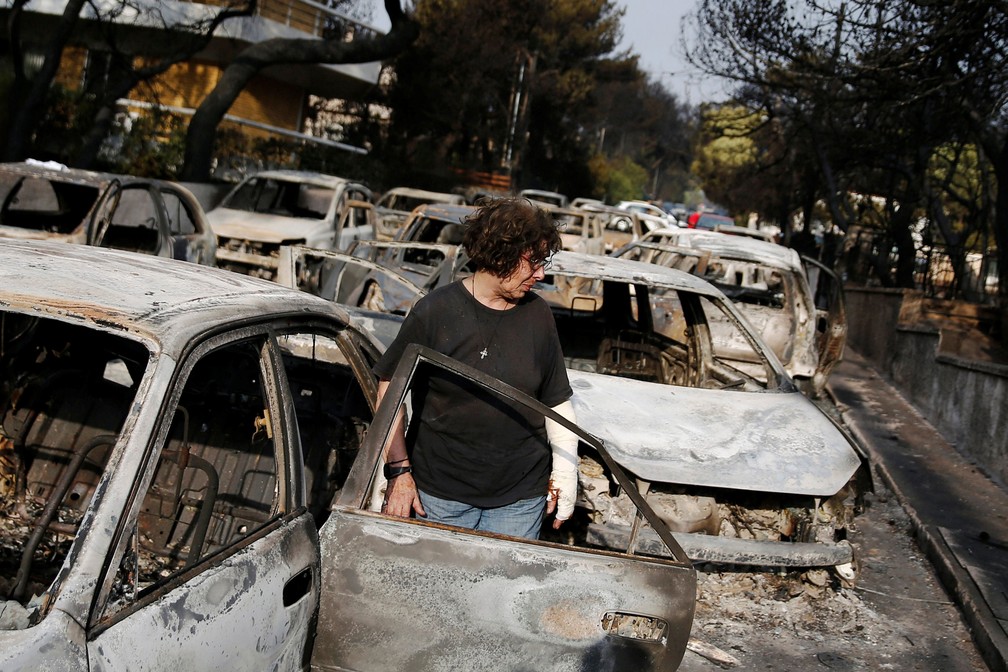 Mulher busca cachorro após incêndio que atingiu Mati, cidade perto de Atenas, nesta terça-feira (24) (Foto: Costas Baltas/ Reuters)