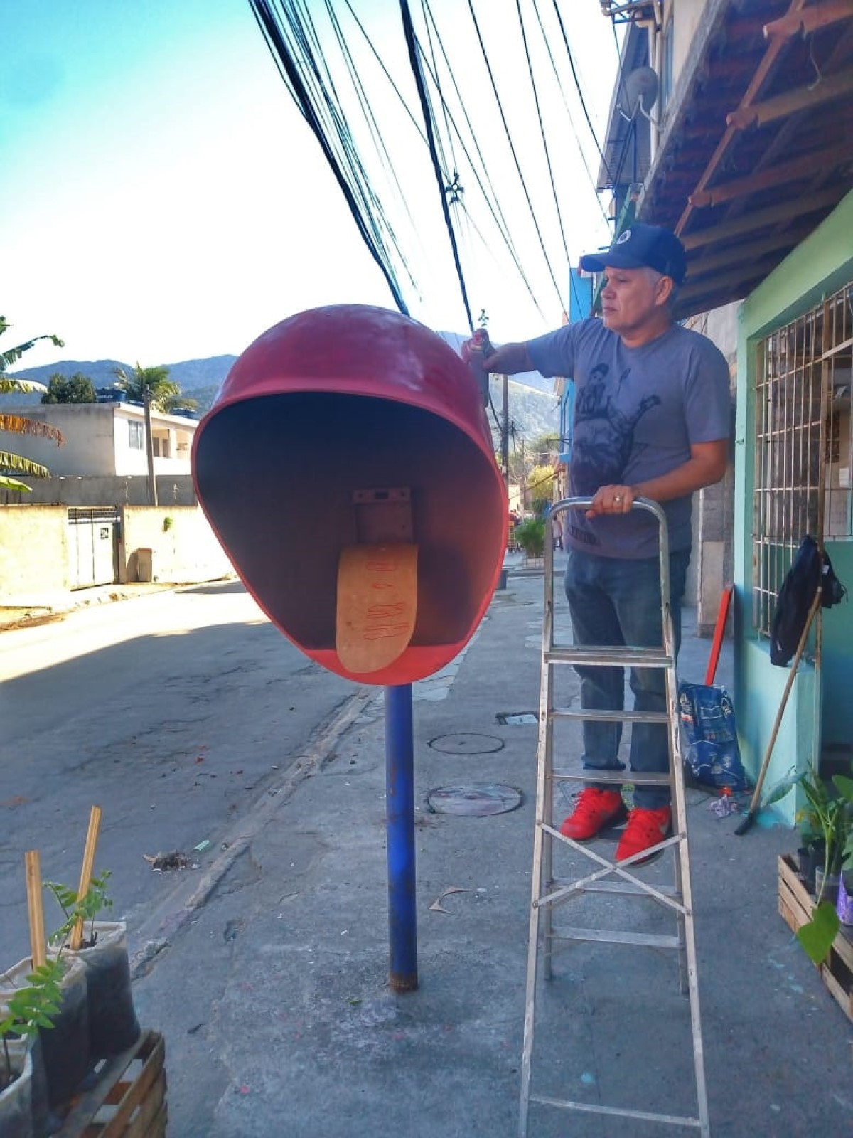 Na foto, Edney Dantas está no início da pintura do orelhão, que fica na frente da loja de plantas de seu amigo, no bairro Bangu, no Rio de Janeiro (Foto: Edney Dantas / Divulgação )