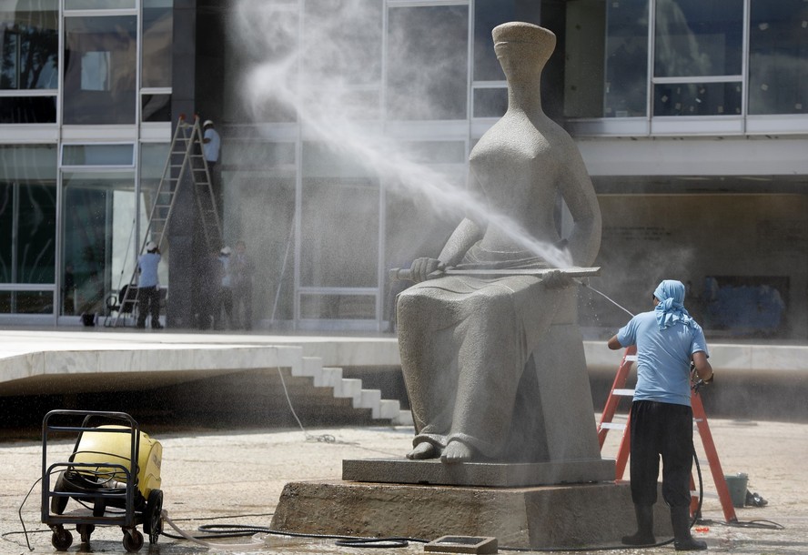 Funcionário do STF limpa estátua pichada por bolsonaristas
