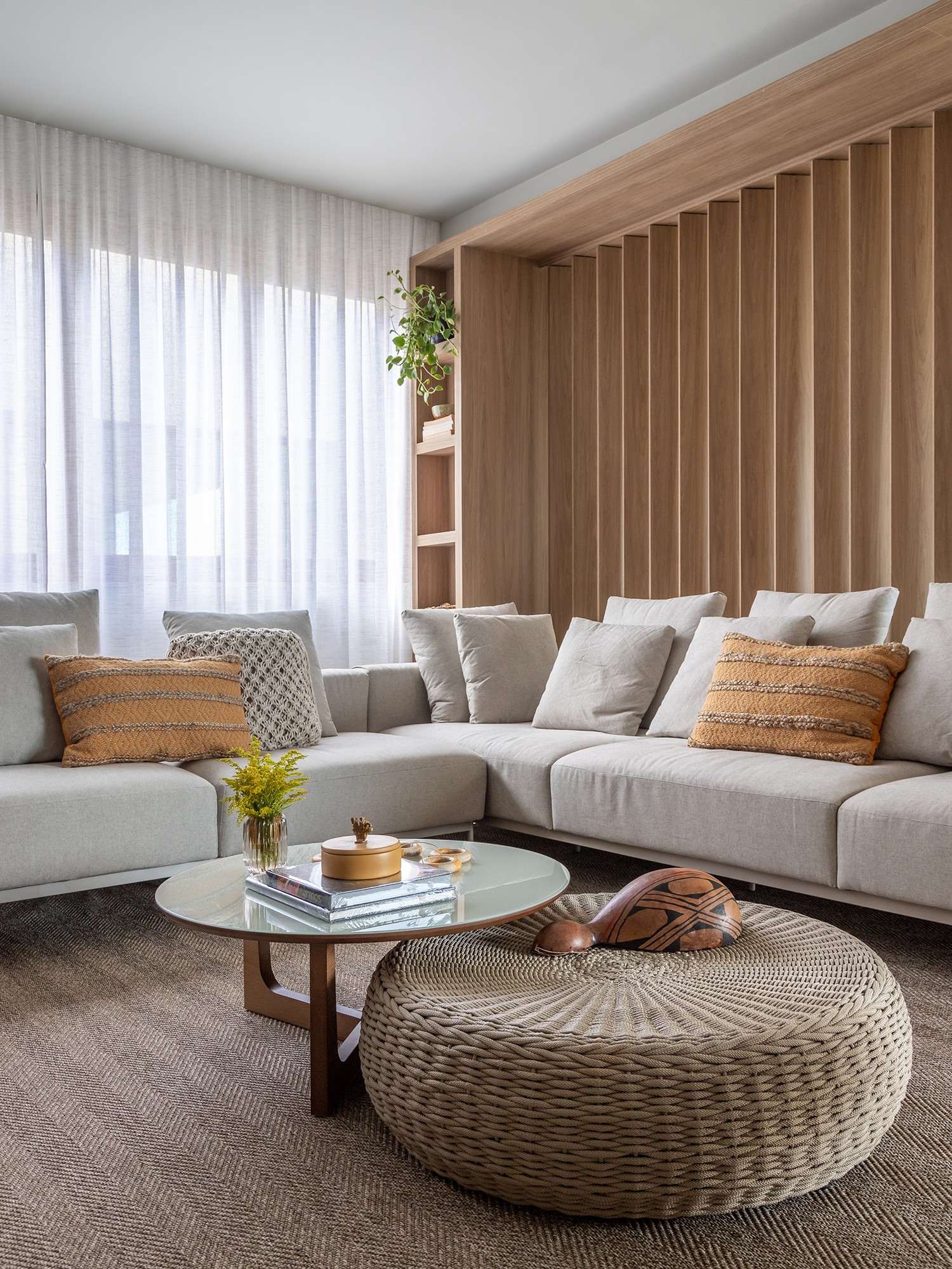 SALA | Atrás do sofá cinza da Home Design Casual, o painel ripado divide a sala e a varanda (Foto: Gabriela Daltro / Divulgação)