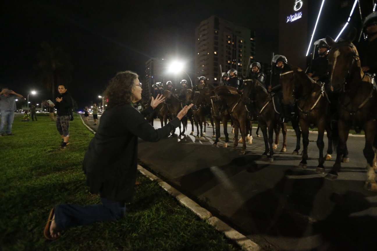 Manifestante se ajoelha diante da cavalaria da polícia.  — Foto: Cristiano Mariz