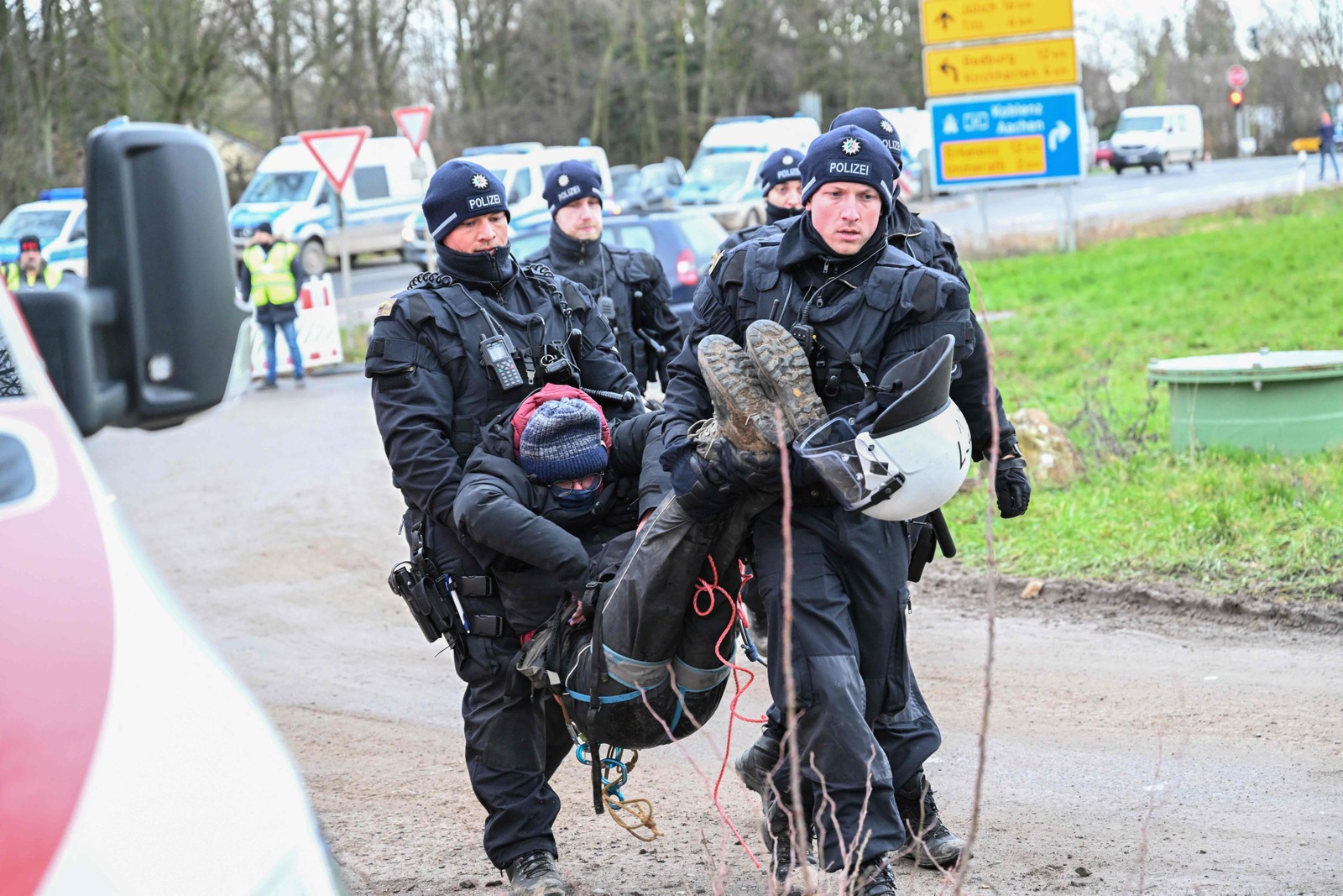 Policiais levam um ativista climático que havia feito rapel de uma ponte da rodovia para protestar contra a demolição da vila de Luetzerath para dar lugar a uma extensão de mina de carvão, no oeste da Alemanha.  — Foto: INA FASSBENDER / AFP