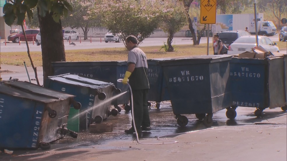 Funcionário limpa contêineres de lixo no Sudoeste (Foto: TV Globo/Reprodução)