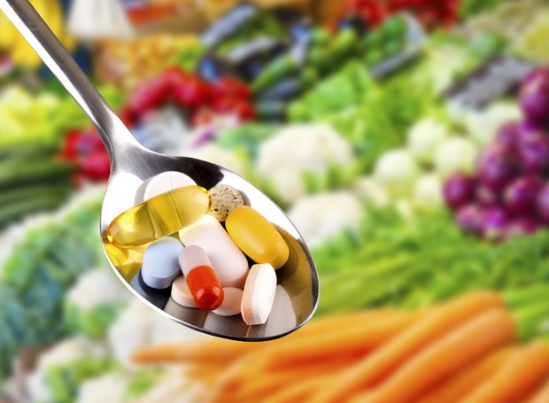 spoon with variety of pills, dietary supplements on blurred vegetables background (Foto: Getty Images/iStockphoto)