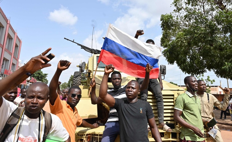 Manifestantes agitam uma bandeira russa enquanto protestam contra a França e a Comunidade Econômica dos Estados da África Ocidental (Cedeao) após o segundo golpe em Burkina Faso em menos de nove meses