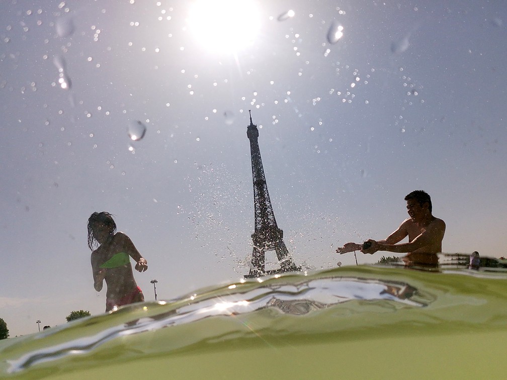 Pessoas tomam banho no Chafariz do Trocadero, ao lado da Torre Eiffel, em Paris, no dia 25 de julho. — Foto: Dominique Faget / AFP