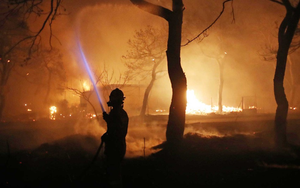 Um bombeiro combate chamas na cidade de Mati, leste de Atenas (Foto: Thanassis Stavrakis /AP Photo)