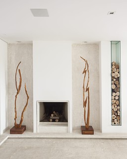 A lareira já existia nessa sala de estar. Para decorar, a arquiteta Ieda Korman, do escritório Korman Arquitetos, projetou nichos para guardar a lenha e esculturas de madeira