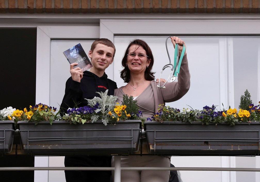 A residente Françoise e seu filho Denis posam na varanda de sua casa com objetos significativos para eles durante isolamento imposto pelo governo belga na tentativa de retardar o surto de doença por coronavírus (COVID-19) em Bruxelas, na Bélgica, em 19 de março — Foto:  Yves Herman/Reuters