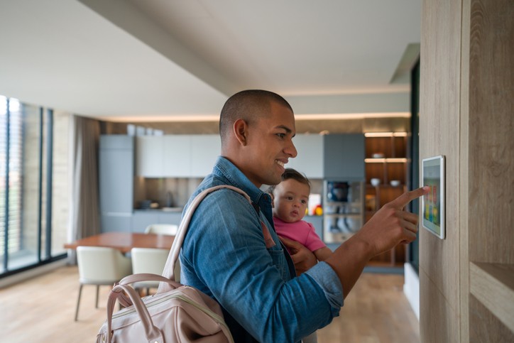 Happy Latin American man leaving the house with his baby and locking the door using a home automation system â smart home concepts (Foto: Getty Images)