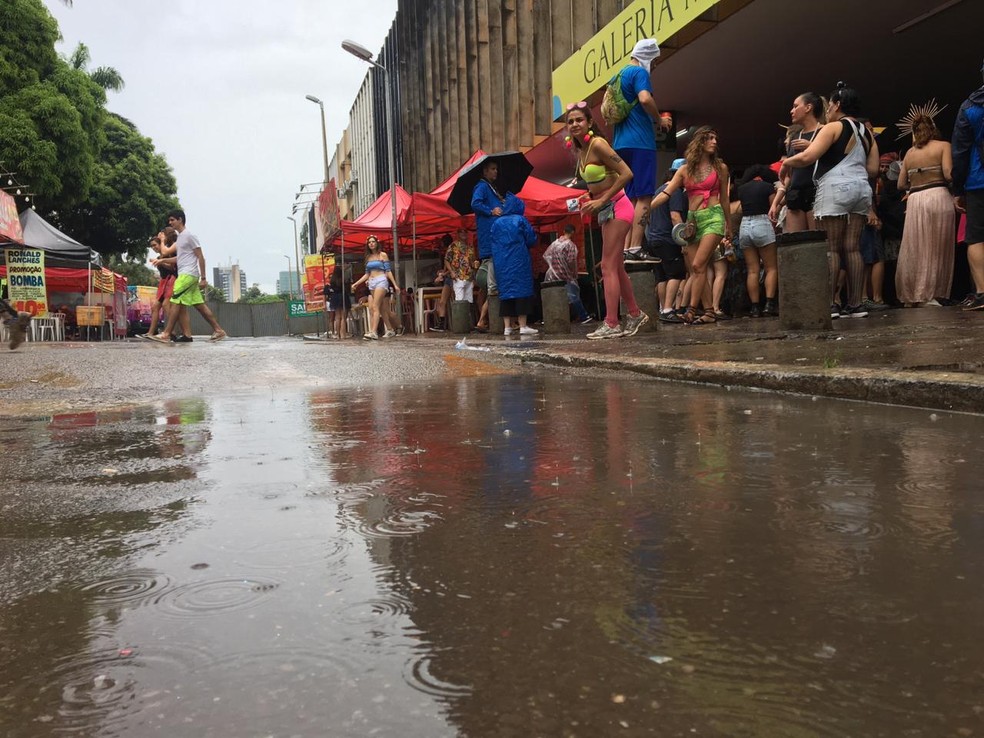 Foliões, em Brasília, procuram marquise para se proteger da chuva no carnaval de rua — Foto: Wellington Valadão/ TV Globo