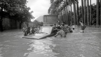 Em temporal de fevereiro de 1988, homens tentam salvar um carro arrastado pela correnteza na Rua Jardim Botânico — Foto: Carlos Ivan/Agência O Globo