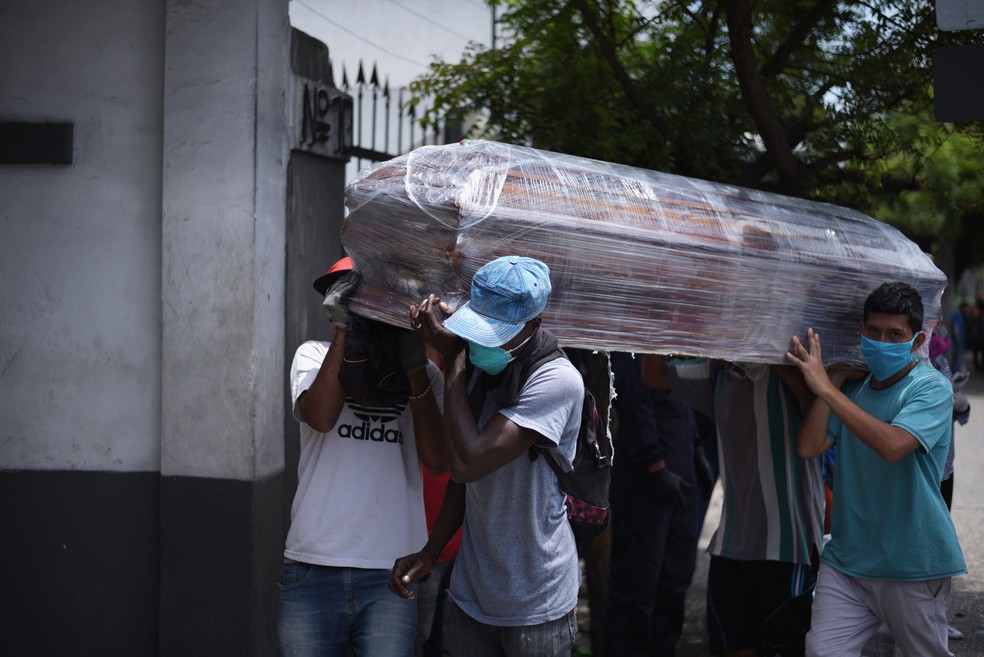 Homens apenas com máscaras carregam caixão para cemitério em Guayaquil, no Equador, no domingo (12)  — Foto: Vicente Gaibor del Pino/Reuters 