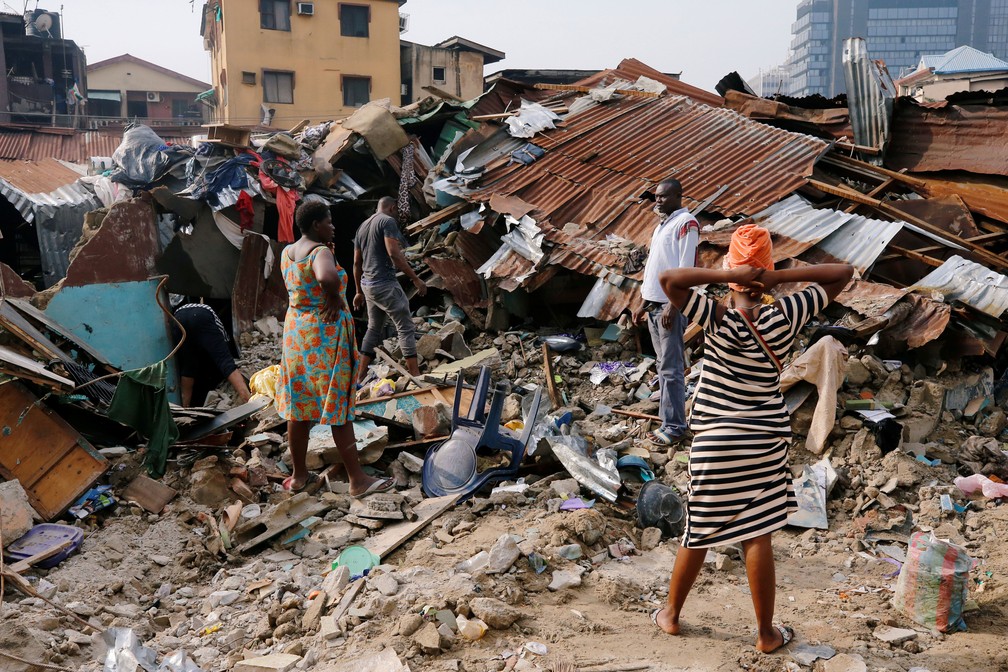 14 de março - Mulher busca pertences entre os destroços de imóvel que desabou em Lagos, na Nigéria — Foto:  Afolabi Sotunde/ Reuters