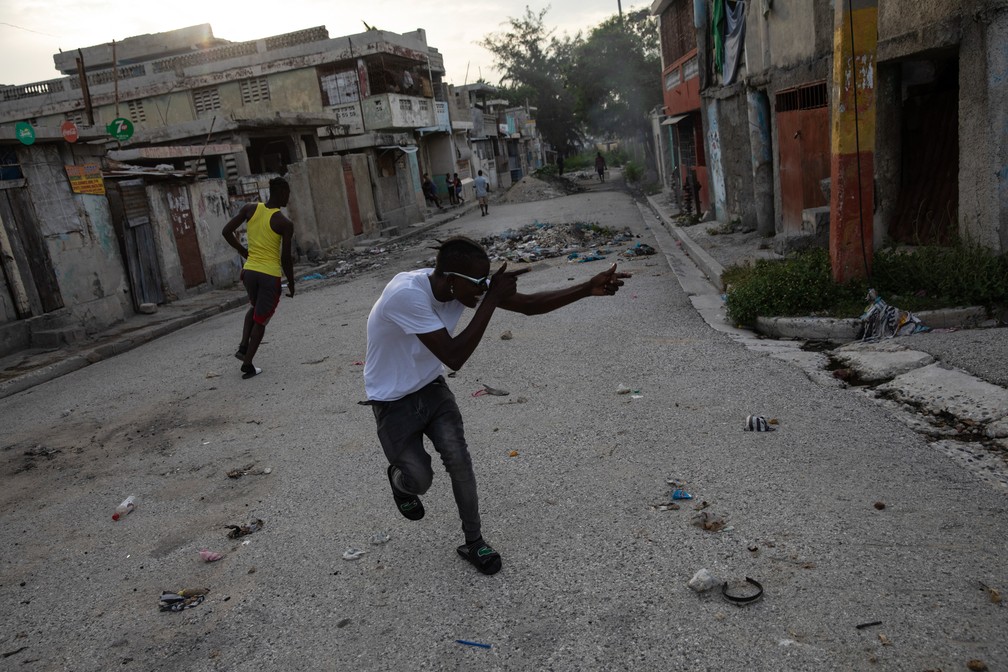 5 de outubro - Um membro de uma gangue aponta uma arma imaginária para uma gangue rival em uma esquina que divide o controle de duas gangues no bairro de Bel Air, em Porto Príncipe, no Haiti  — Foto: Rodrigo Abd/AP