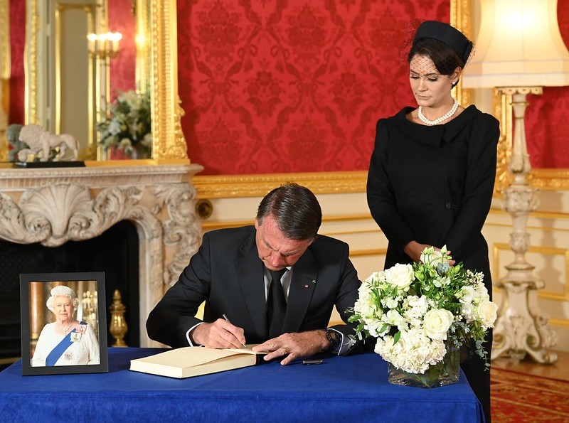 O presidente Jair Bolsonaro assina o livro de condolências. Ao lado dele, a primeira-dama Michelle Bolsonaro observa — Foto: Jonathan Hordle/PA Media Assignment