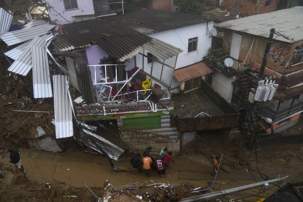 Moradores e voluntários retiram o corpo de uma vítima dos deslizamentos em Petrópolis (RJ) nesta quarta (16)  — Foto: Silvia Izquierdo/AP