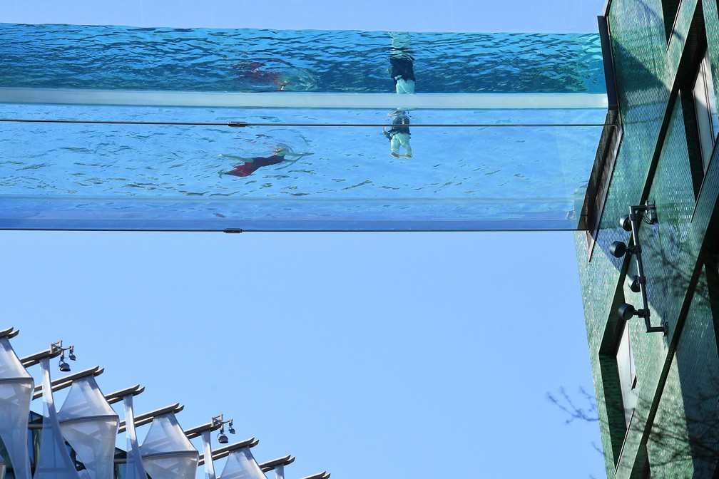 Uma modelo nada em uma piscina de acrílico transparente fixada entre dois blocos de apartamentos em Embassy Gardens, em Londres — Foto: Justin Tallis/AFP