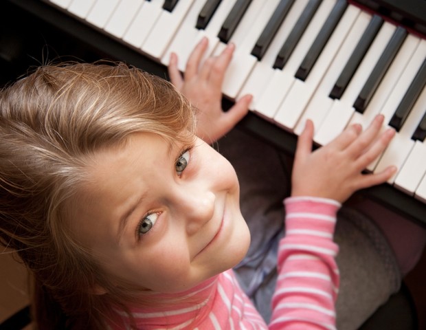 Menina aprende a tocar piano com música online para ensino à