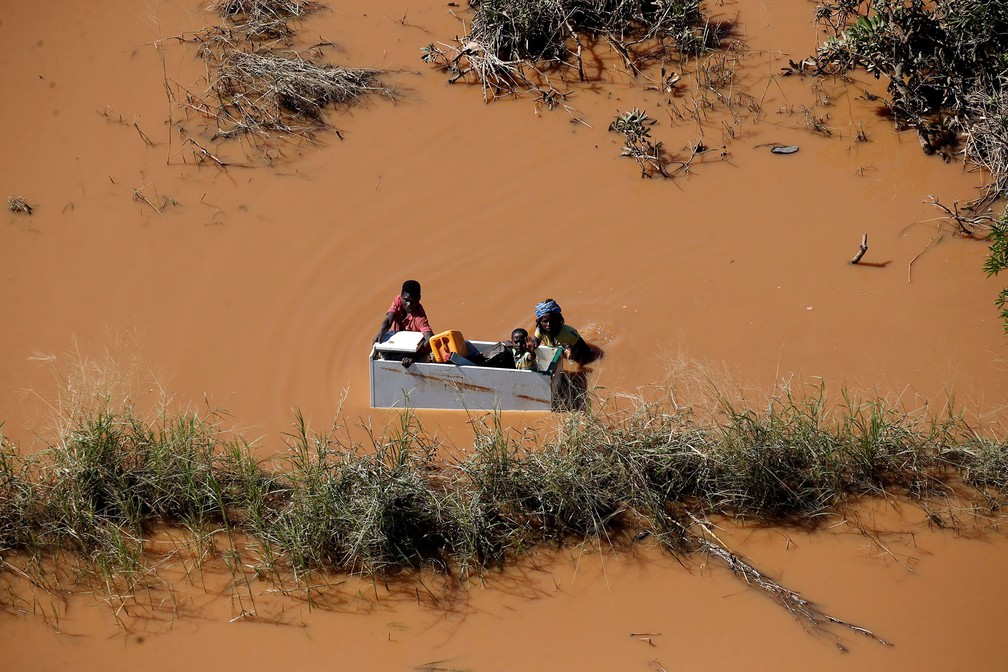 Casal usa a carcaÃ§a de uma geladeira como bote para transportar uma crianÃ§a e pertences atravÃ©s de Ã¡rea alagada em Buzi, perto da cidade de Beira, em MoÃ§ambique, numa das regiÃµes mais devastadas pela passagem do ciclone Idai â Foto: Siphiwe Sibeko/Reuters