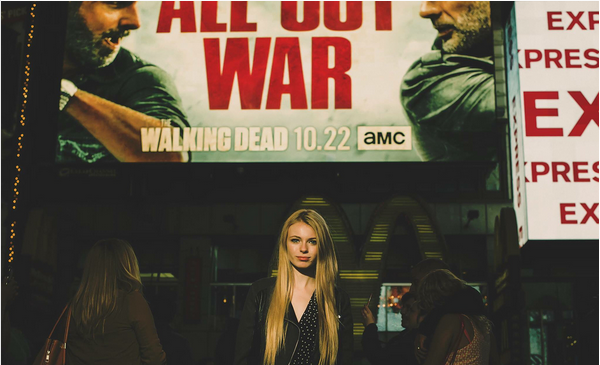 A atriz Addy Miller em frente a um anúncio de The Walking Dead (Foto: Instagram)