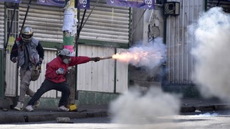 Manifestante lança rojão contra policiais durante protesto de plantadores de folha de coca em La Paz, Bolívia — Foto: AIZAR RALDES / AFP