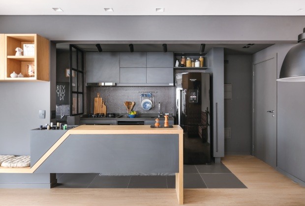 Para dar sensação de maior profundidade, a cozinha americana de 5,40 m² é como uma caixa escura separada do restante do apartamento (Foto: Mariana Orsi / Divulgação)
