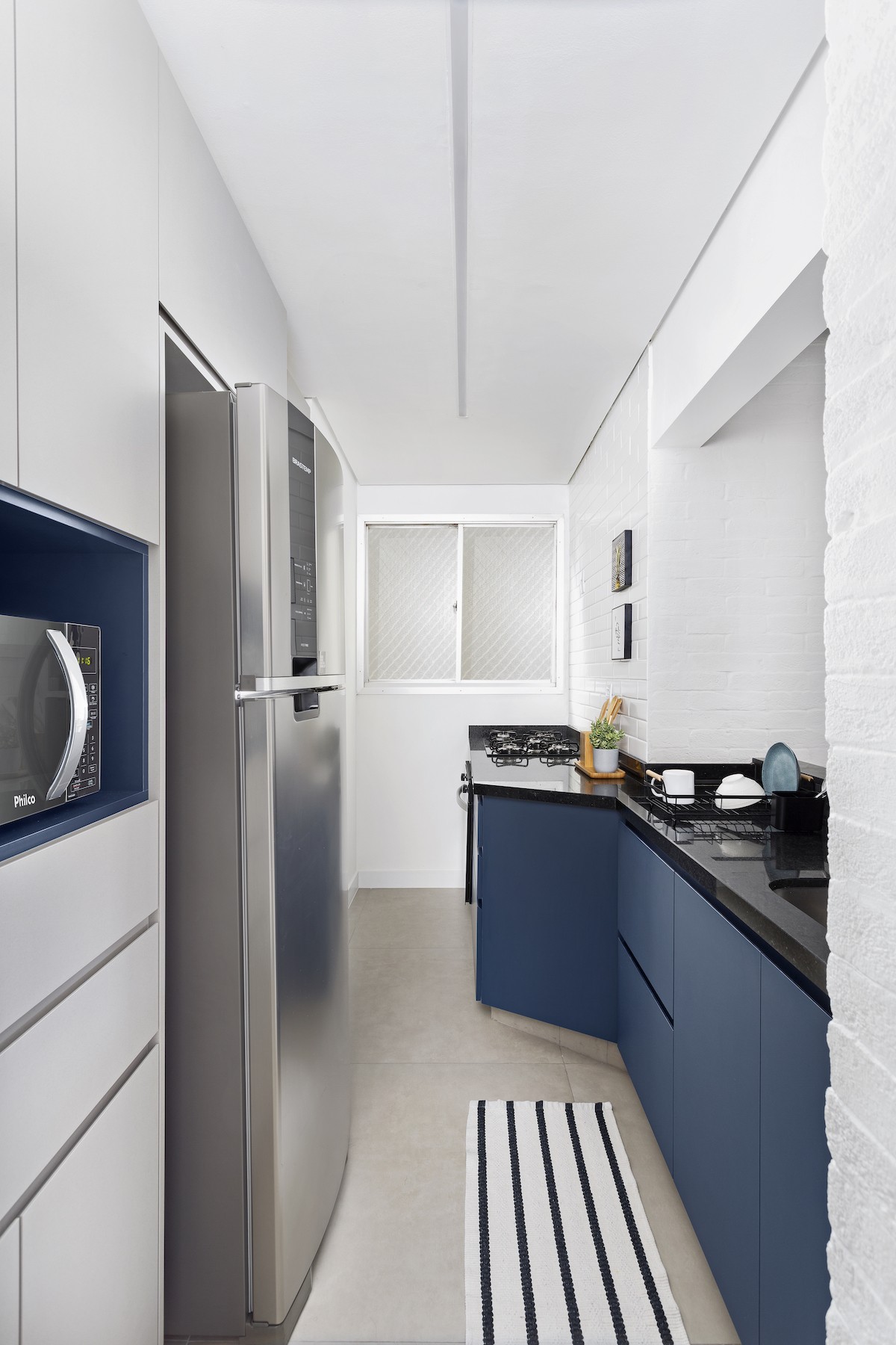 COZINHA | Também em formato de corredor, a cozinha ganhou soluções de armazenamento extra com os armários dispostos nela  (Foto: Divulgação / Julia Ribeiro)