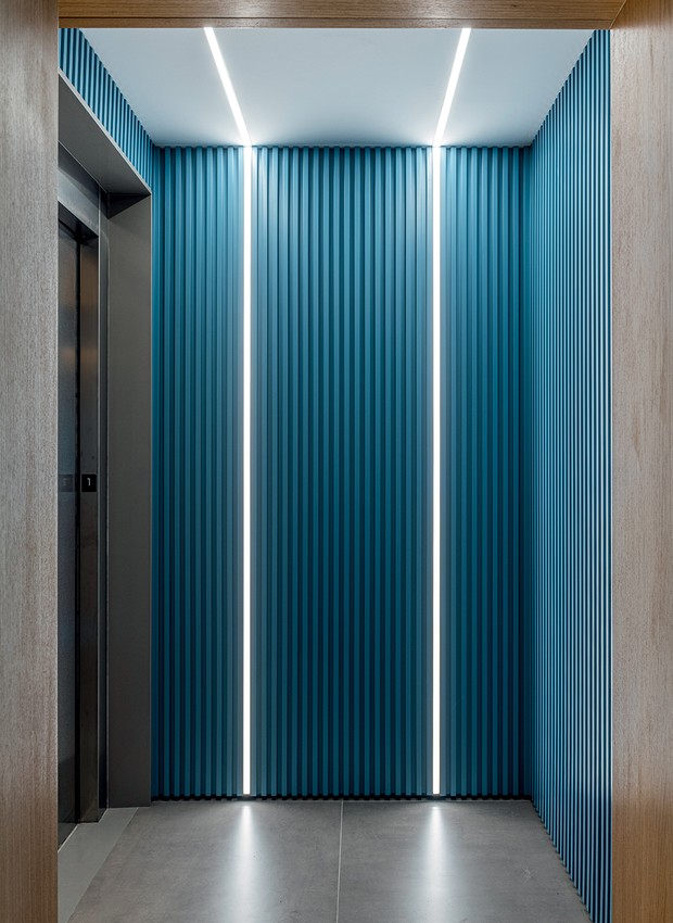 Paredes com ripado tingido de azul marcam o hall de entrada, com iluminação de led com sensor de presença  (Foto: Renato Navarro / Divulgação)