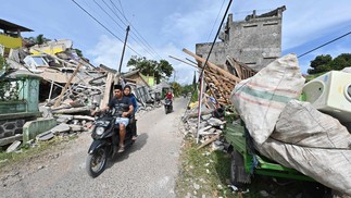 Motoristas passam por casas danificadas em Cugenang, Cianjur, após o terremoto que atingiu a área em 21 de novembro — Foto: ADEK BERRY / AFP