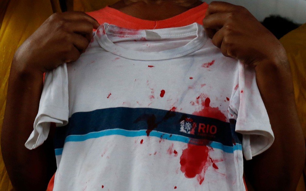 Tia Ketellen segura camiseta de escola suja de sangue no enterro  — Foto: Ian Cheibub/Reuters
