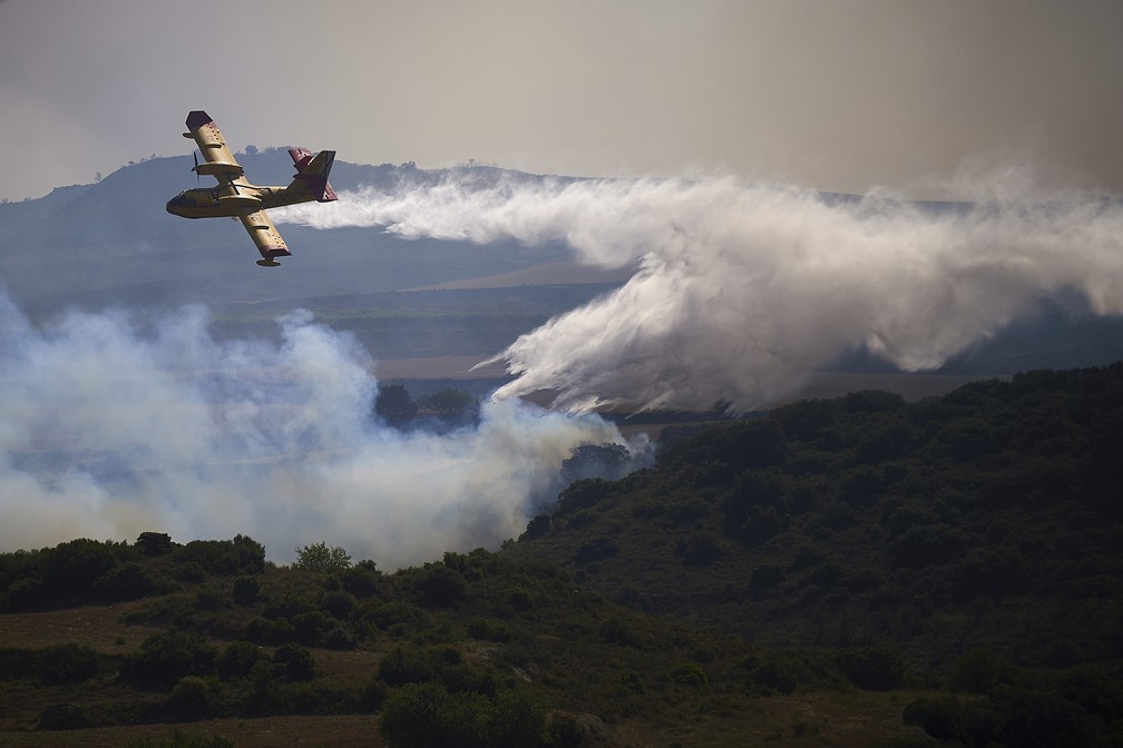 Avião do corpo de bombeiros apaga fogo em uma área de queimada em San Martin de Unx, ao norte da Espanha (19/06/2022). — Foto: ASSOCIATED PRESS