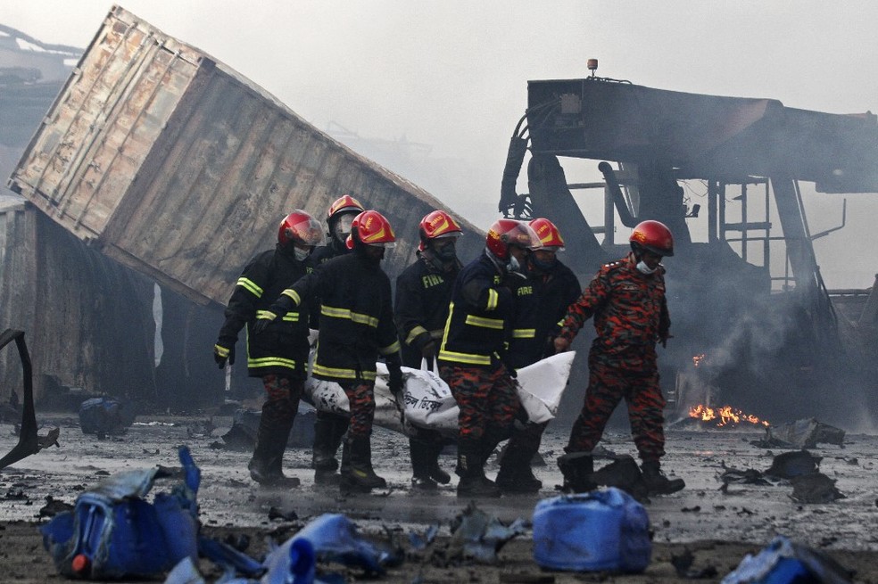 Equipes retirar corpo de vítima do incêndio em depósito de contêineres em Bangladesh — Foto: AFP