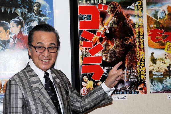Akira Takarada em foto de 2013 posando ao lado do pôster Godzilla (1954) (Foto: Getty Images)