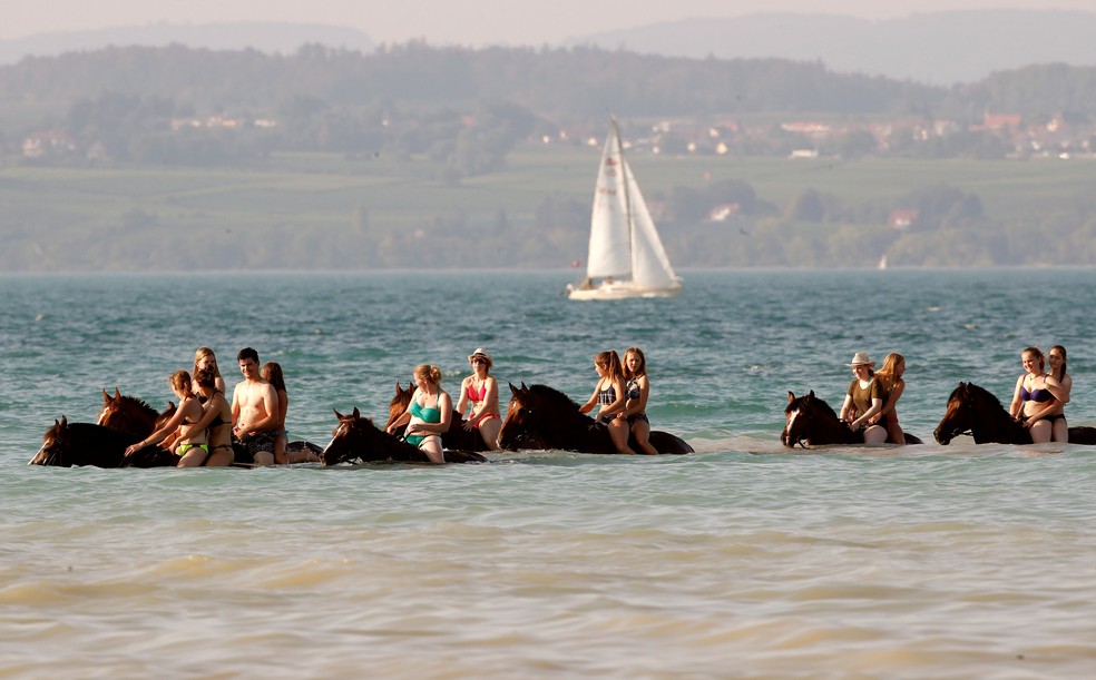 Banhistas cavalgam dentro da água do Lago Constança, perto de Güttingen, na Suíça. País também foi atingido por onda de calor neste verão europeu (Foto: Reuters/Arnd Wiegmann )
