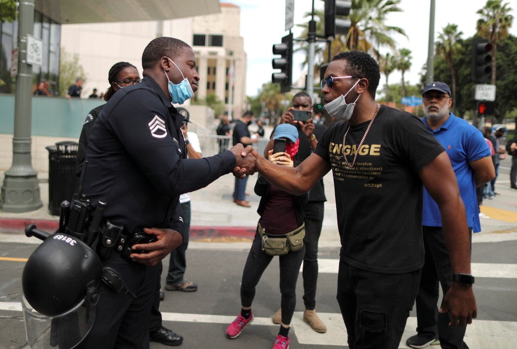 Um policial aperta a mão de um manifestante durante um protesto contra a morte de George Floyd do lado de fora da sede da polícia de Los Angeles, nos EUA, na terça-feira (2) — Foto: Lucy Nicholson/Reuters