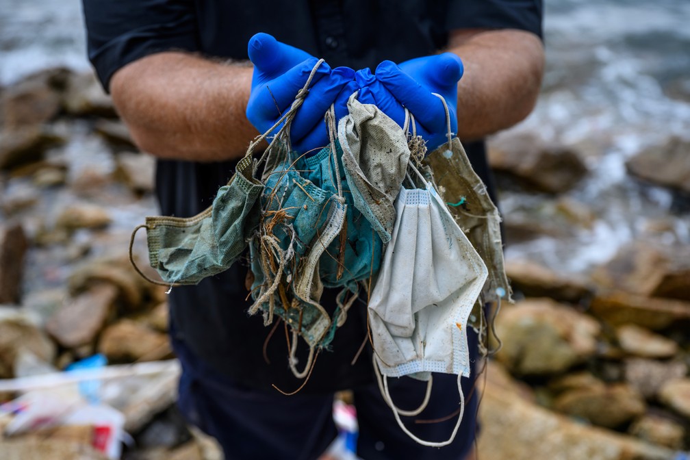 Na foto, de 13 de maio, Gary Stokes, fundador do grupo ambiental Oceans Asia, segura máscaras que encontrou em uma área residencial perto de uma praia em Hong Kong. — Foto: Anthony Wallace / AFP