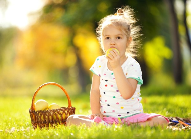 Criança comendo frutas em piquenique ao ar livre (Foto: Shutterstock)