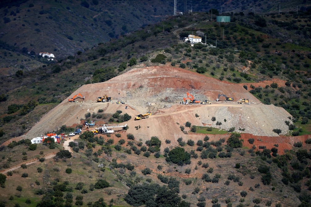 Uma broca é vista ao lado de escavadores e caminhões que retiram areia na área onde um menino caiu em um poço profundo em Totalán, na Espanha.. — Foto: Jon Nazca/Reuters