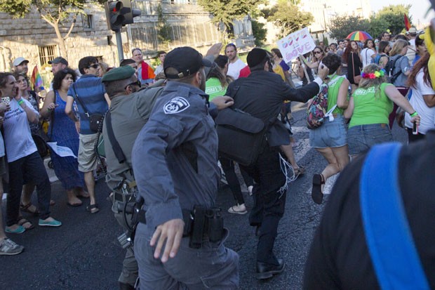Policiais tentam conter um judeu ultraortodoxo que atacava pessoas com uma faca na Parada Gay de Jerusalém nesta quinta-feira (30) (Foto: Sebastian Scheiner/AP)