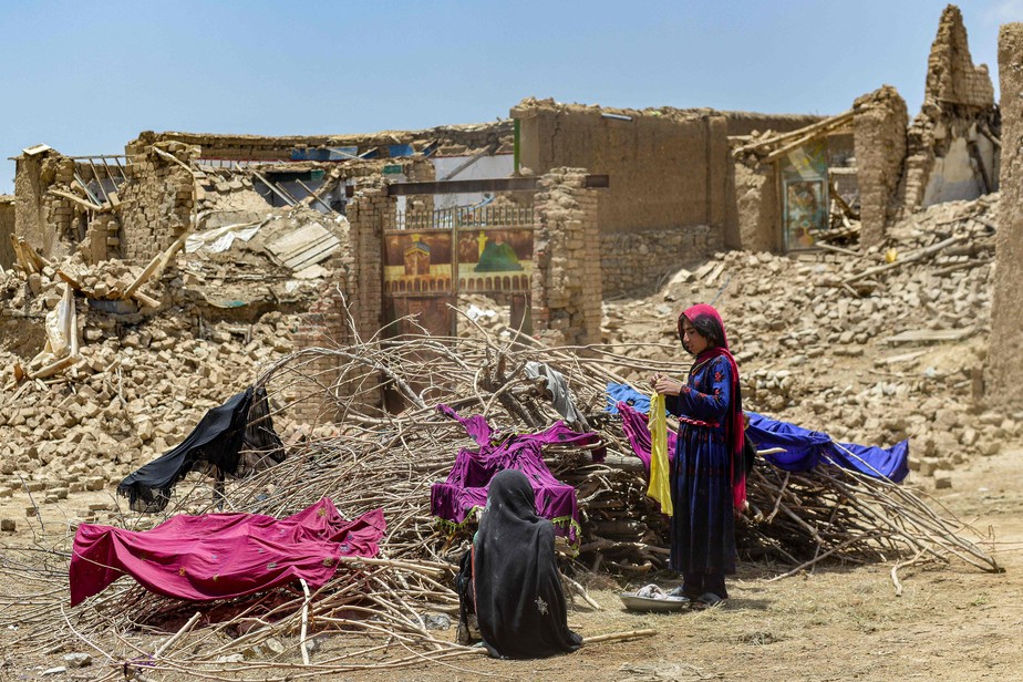 Afegãos mantêm roupas para secar em arbustos secos perto das ruínas de casas danificadas por um terremoto no distrito de Bernal, província de Paktika