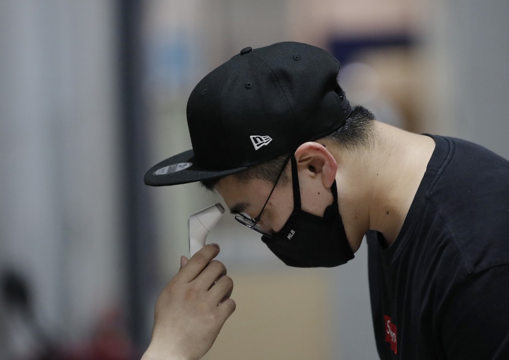 Um homem usando uma m&aacute;scara facial contra a propaga&ccedil;&atilde;o do novo coronav&iacute;rus tem sua temperatura medida no pr&eacute;dio do Sejong Arts Group em Seul, na Coreia do Sul, nesta ter&ccedil;a-feira (21) &mdash; Foto: Lee Jin-man/AP
