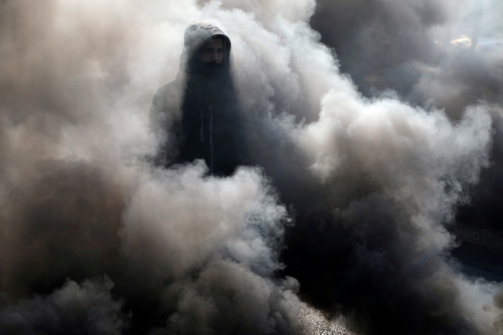 20 de janeiro - Iraquiano passa pela fumaça de pneus queimados durante protestos contra o governo em Kerbala — Foto: Abdullah Dhiaa al-Deen/Reuters