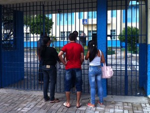 Josileide vê o portão fechado com criança no colo junto a dois outros candidatos (Foto: Amorim Neto/G1)