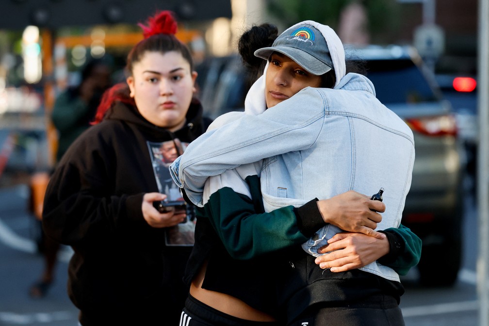 Pessoas se abraçam no local do tiroteio na Califórnia, nos Estados Unidos, neste domingo (3) — Foto: REUTERS/Fred Greaves