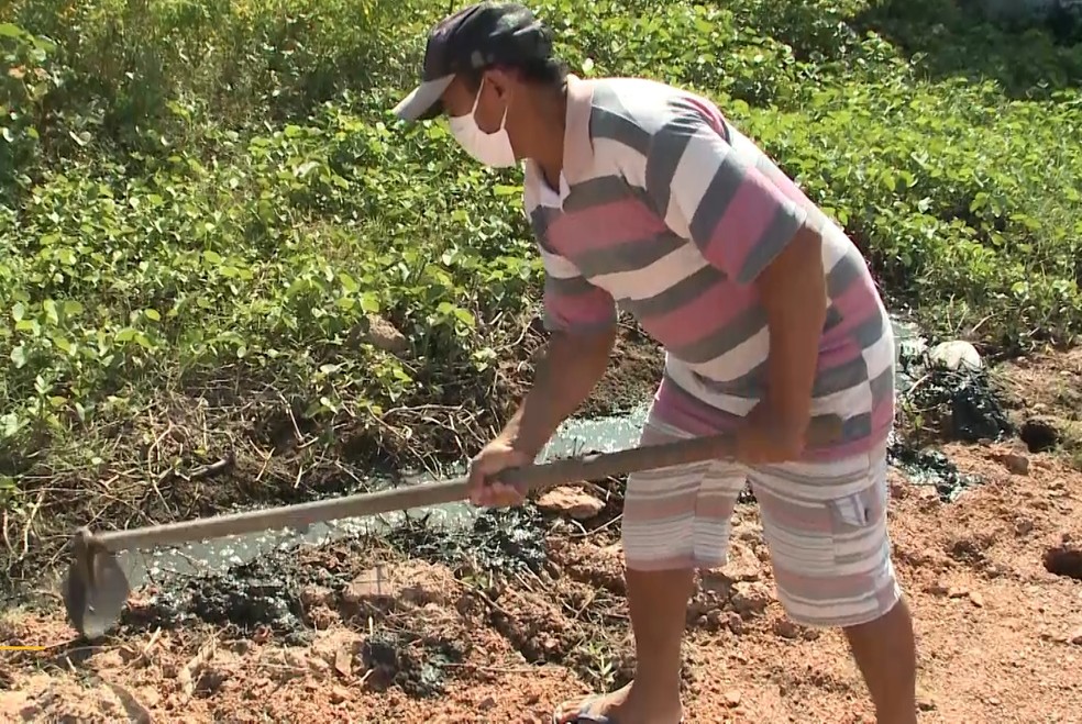 Antônio Ferreira Pereira tenta canalizar o esgoto, mas isso não o livra do mal cheiro — Foto: TV Cabo Branco/Reprodução